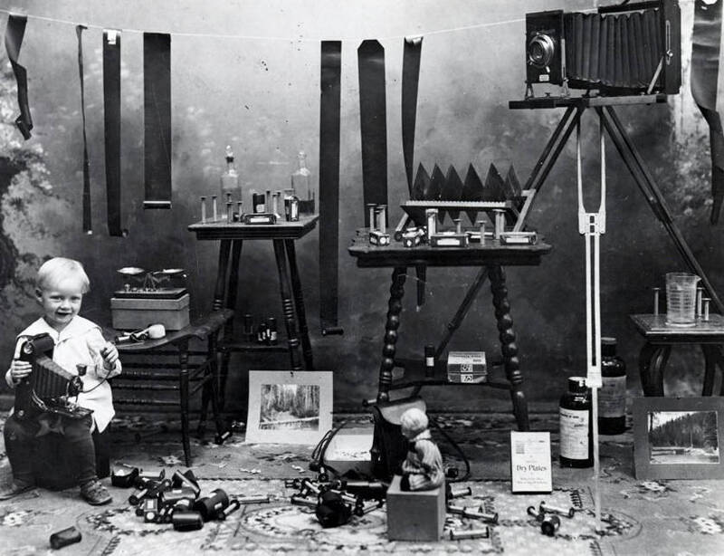Harold, son of A.M. Whelchel, holding camera. Also shows film, tables, chemicals, etc.