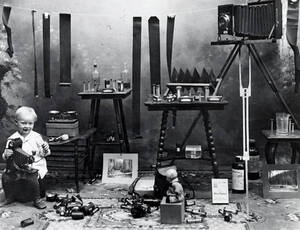 Harold, son of A.M. Whelchel, holding camera. Also shows film, tables, chemicals, etc.
