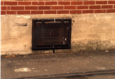Black iron coal door in alley